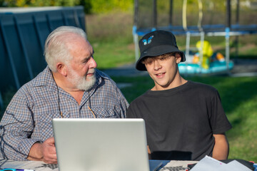 Grandfather explains how to use laptop to his grandson.