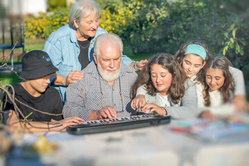 Grandfather playing outdoor with his grandchildren with music in the garden
