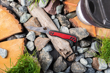 Swiss folding knife on stones. Officer's serrated knife. Knife and carbine. Knife tourism and hiking. Top.