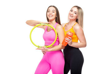 Two beautiful, athletic, slim and cheerful female friends are smiling and holding a hoop and a...