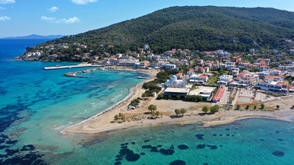 Aerial drone photo of iconic picturesque village, main port and beautiful turquoise beaches of Skala featuring landmark church of Agioi Anargiroi, Agistri island, Saronic gulf, Greece