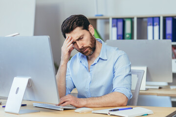 Pensive and upset man working a day in a modern office, businessman holding his hand home longing depressed