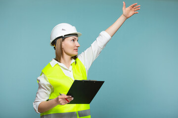 Professional engineer. A woman in a hardhat and bright jelly is using a tablet, on a blue background. Copy paste.