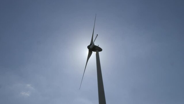 &Eacute;olienne en fonctionnement sur un fond de ciel bleu ensoleill&eacute;. la silhouette de l'&eacute;olienne se d&eacute;tache en contre jour. vid&eacute;o 4K
