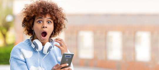 girl with mobile phone and headphones in the street and expression of surprise