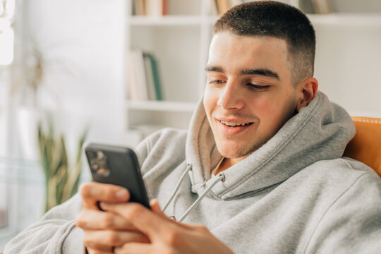 Young Teenager At Home Looking At Mobile Phone