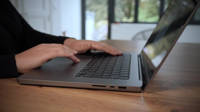 Femme qui travaille sur un ordinateur portable. Gros plan sur les mains et le clavier. Plan en travelling lent. Vid&eacute;o 4K