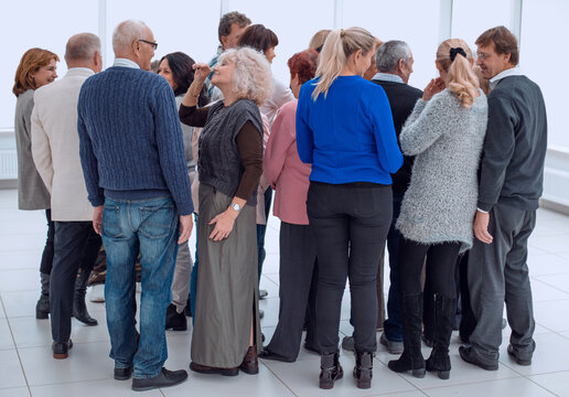 a group of old people standing with their backs indoors