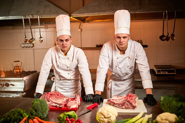 А team of professional chefs cook meals in the kitchen of restaurant.  Chief chef preparing dish using different food ingredients, vegetables,cabbage and meat