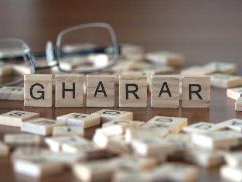 gharar word or concept represented by wooden letter tiles on a wooden table with glasses and a book