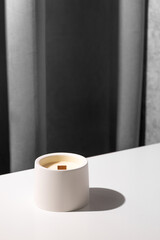 Candle soy homemade in ceramic burning in grey modern interior room, atmosphere and minimalistic composition 