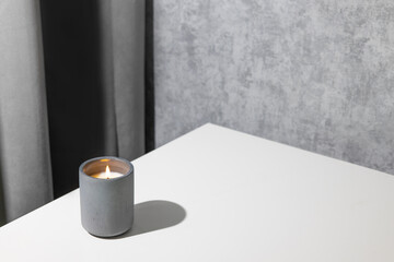 Candle soy homemade in ceramic burning in grey modern interior room, atmosphere and minimalistic composition 
