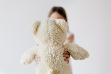 rearview of white teddy bear - unrecognizable little girl holding her stuffed plush for sleeping