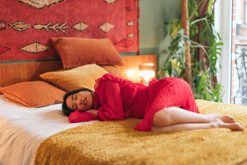 beautiful asian woman in red dress sleeping on bed