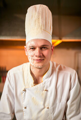 Portrait of professional pastry cook. Chef prepares dough with flour in a professional kitchen to make bread, Italian pasta or pizza. Baking food concept