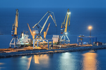 Sea commercial port at night in Mariupol, Ukraine before the war. Industrial. Cargo freight ship...