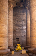 Woman with yellow dress between the pillars of the Temple of Edfu, Egypt