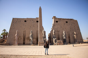 Woman looking at Luxor temple, blue sky day, Egypt
