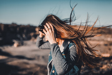 The girl on the mountain puts on her glasses and runs away. The wind blows the hair in the sunlight.