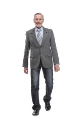 full length picture of a mid aged business man walking towards the camera and smiling.