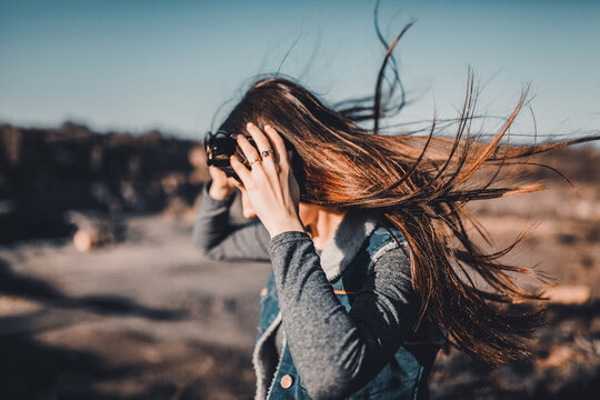 The girl on the mountain puts on her glasses and runs away. The wind blows the hair in the sunlight.