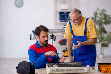 Two male repairmen repairing air-conditioner