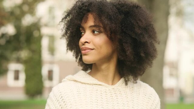 Beautiful African American curly brunette looking around and asking to be quiet with serious look. Attractive young girl in the park. High quality 4k footage