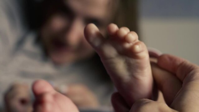 Close-up. Mom tickles her baby's little heel with her fingers
