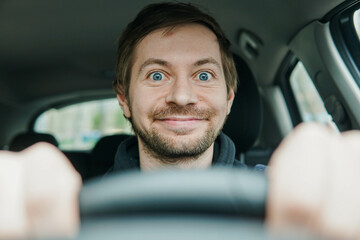 Close up portrait of happy excited driver begginer behind the wheel of his first car.