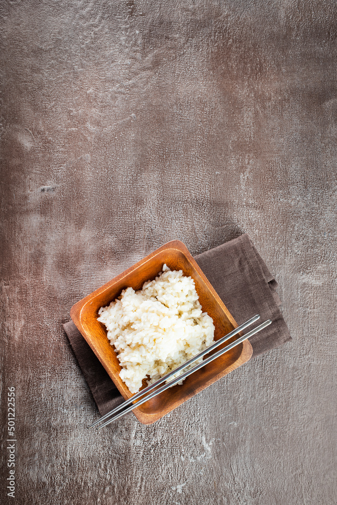 Sticker bowl of boiled rice and sticks on dark table