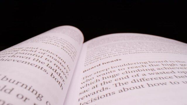 SUPER SLOW MOTION, CLOSE UP, PROBE LENS: Close up overview of open book pages in slow motion. Pull back shot of printed open book pages. Probe lens shot of content in the open book.