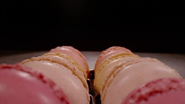 SUPER SLOW MOTION, CLOSE UP, PROBE LENS: Close up overview of sweet macarons in pastel colours in slow motion. Pull back shot of lined up French confectionery. Detailed view of delicious temptation.