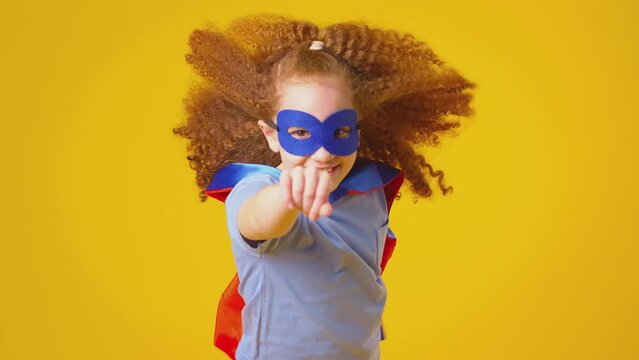 Studio Portrait Of Girl Dressed As Comic Book Superhero Against Yellow Background