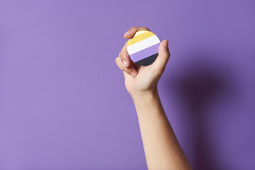Hand raising a non binary flag badge; gender diversity, identity pride