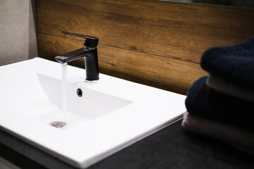 Close-up, bathroom interior, washbasin with mirror, black faucet and dark towels