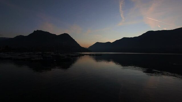 Sunrise on the lugano lake with mountains reflections on placid waters. Ticino, Switzerland