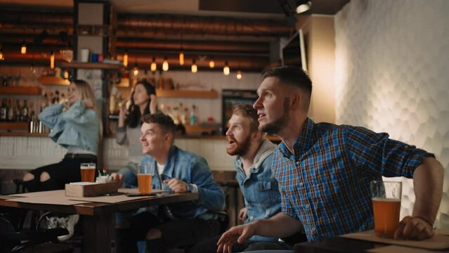 Friends are watching together emotionally watching football on TV in a bar and celebrating the victory of their team after scoring a goal. Watch hockey. The scored puck. 