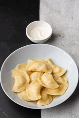 Traditional ukrainian dish vareniki served in a bowl with sour cream. Close up view of traditional Ukrainian food.