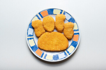 Uncooked breaded semi-finished schnitzel on a plate in the shape of a dog paw footprint