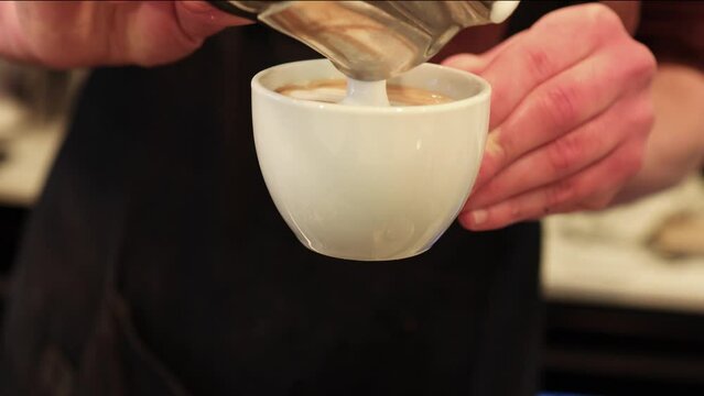 barman fazendo cappuccino colocando leite na x&iacute;cara e criando espuma na bebida.