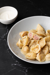 Meat dumplings, homemade russian pelmeni in bowl isolated on black background with clipping path