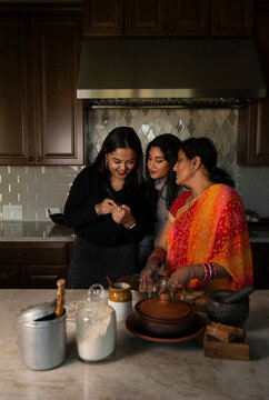 Daughters and mother looking at the cellphone in the kitchen 
