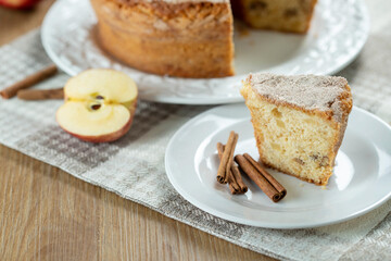 piece of Sponge cake or chiffon cake with apples so soft and delicious sliced ​​with ingredients: cinnamon, eggs, flour, apples on wooden table. Home bakery concept for background and wallpaper