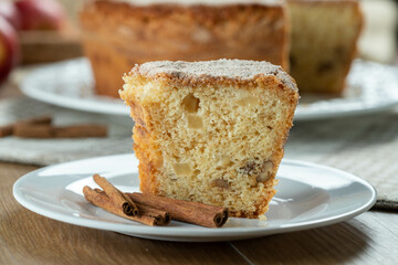 piece of Sponge cake or chiffon cake with apples so soft and delicious sliced ​​with ingredients: cinnamon, eggs, flour, apples on wooden table. Home bakery concept for background and wallpaper
