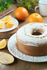 Moist orange fruit cake on plate with orange slices on wooden table. Delicious breakfast, traditional English tea time. Orange cake recipe.
