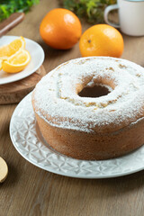Moist orange fruit cake on plate with orange slices on wooden table. Delicious breakfast, traditional English tea time. Orange cake recipe.