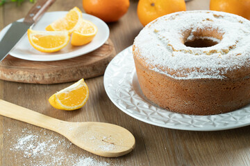 Moist orange fruit cake on plate with orange slices on wooden table. Delicious breakfast, traditional English tea time. Orange cake recipe.
