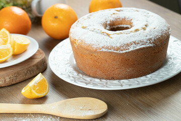 Moist orange fruit cake on plate with orange slices on wooden table. Delicious breakfast, traditional English tea time. Orange cake recipe.