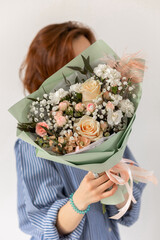 Delicate bouquet with gypsophila and roses in green packaging