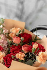 A bright bouquet of flowers in beige packaging. Red roses, Mattiol, Ranunkulus, bush cloves. Flowers in black chair